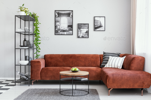 Black and white gallery of photos above brown velvet corner sofa Stock